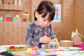 toddler girl  making craft by using cardboard for homeschooling