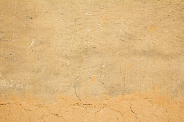 Old brown clay wall with rough and cracked surface texture background.