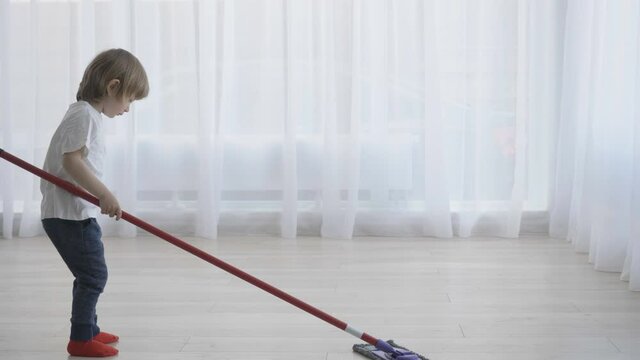 Diligent little child with mop wash floor, early responsibility