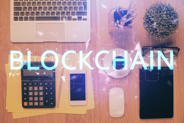 Double exposure of blockchain theme hologram over table with phone. Top view. Crypto technology...