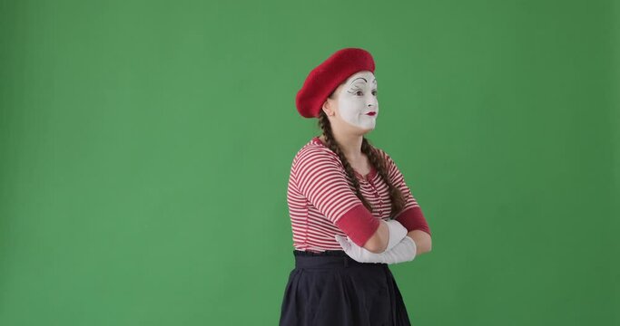 Disgusted female mime artist trying to ignore something bad over green background
