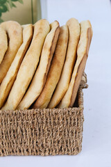 Fresh round pita bread in a wicker basket. Round pita bread with a hole, flat unleavened white bread, flat bread baked in a tandoor. Ready-made fresh pita bread stands on wooden shelves in the store,