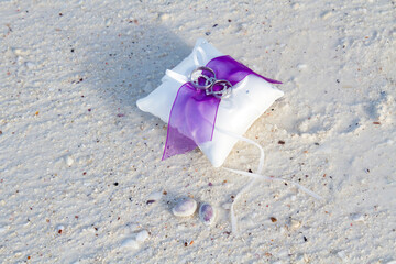 Wedding rings with purple lace on a white sand beach closeup shot 