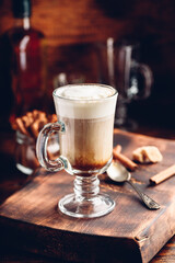 Coffee with Irish whiskey and whipped cream in glass on rustic wooden surface