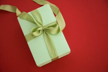 Girl holds a gift box and unties the bow. a girl opens a gift box. Gift box on a red background. Girl unties the tape from the box.
