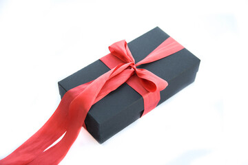 Girl holds a gift box and unties the bow. a girl opens a gift box. Gift box on a red background. Girl unties the tape from the box.
