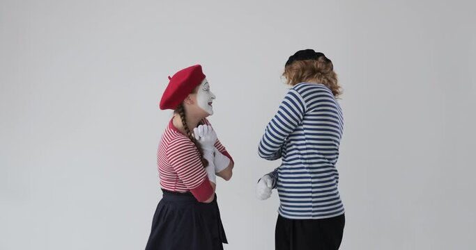 Funny mime artist couple feeling shy over white background