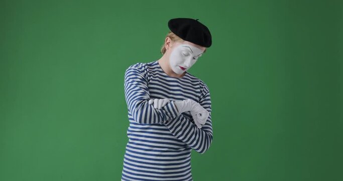 Impatient man mime artist checking time while waiting for someone over green background