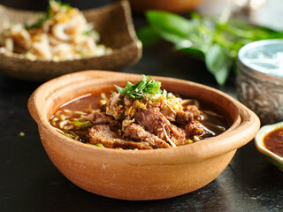 thai bowl of beef noodle soup in clay pot with duck liver