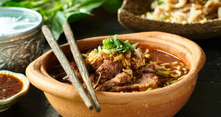 thai bowl of beef noodle soup in clay pot with duck liver