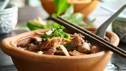 thai bowl of beef noodle soup in clay pot with duck liver