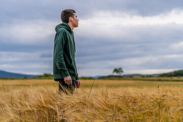 Naklejka na ściany i meble boy in sportswear in a wheat field strolls thoughtfully into the sunset