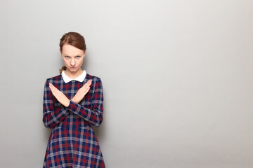 Portrait of serious girl making cross with hands, showing stop gesture