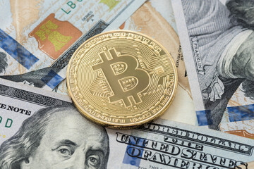 Gold Bitcoin on hundred dollars bills. Close-up, macro shot.