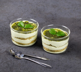 italian dessert tiramisu with green matcha tea in a glass Cup on a dark background