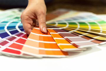 The hand of the designer shows a color palette. Catalog of rainbow color samples.
