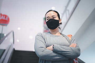 Young asian woman wearing surgical mask in shopping mall. New normal and lifestyle concept with COVID-2019.