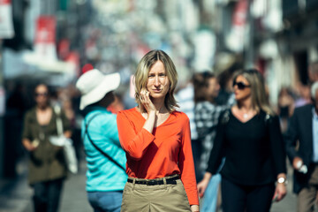 Woman in a red blouse posing on a pedestrian street.