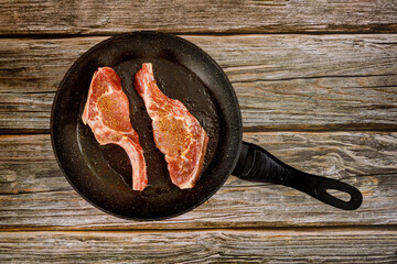 Raw pork steak on cast iron skillet on wooden background. - Powered by Adobe