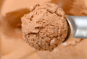 top view spoon taking out an ice cream ball from box of chocolate flavor ice cream