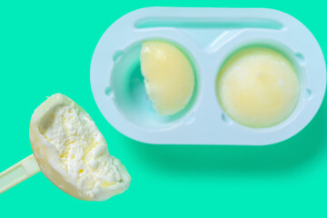 top view spoon taking out vanilla flaovr mochi dessert ice cream on green background