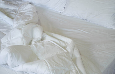 Close-up of clean white soft pillows with duvet and bed sheets on the comfortable bed in the bedroom.