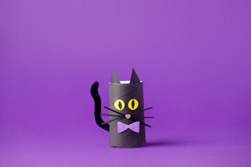 Halloween black cat on purple for Halloween concept background. Paper crafts, easy DIY. Handcraft creative idea from toilet tube for daycare, kindergarten, recycle concept, copy space