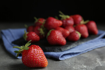 Many delicious ripe strawberries on grey table