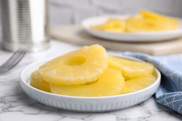 Tasty canned pineapple slices on white marble table, closeup