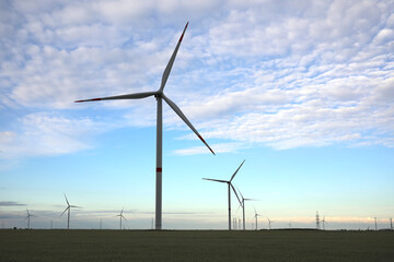 Beautiful view of field with wind turbines in evening. Alternative energy source