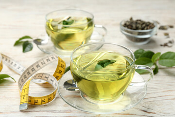 Diet herbal tea with green leaf and measuring tape on white wooden table