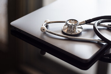 Medical stethoscope and laptop computer isolated on dark background. Medic tech, online medical,...