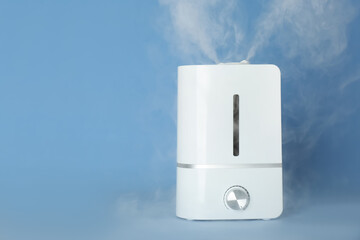 Modern air humidifier on light blue background. Space for text