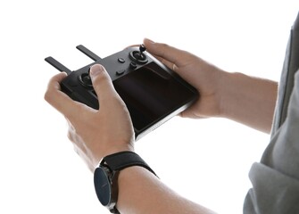 Man holding new modern drone controller on white background, closeup of hands © New Africa