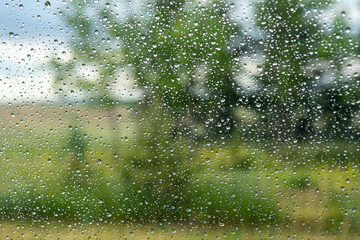 Rain drops on a car window looking out at the plains and the sky
