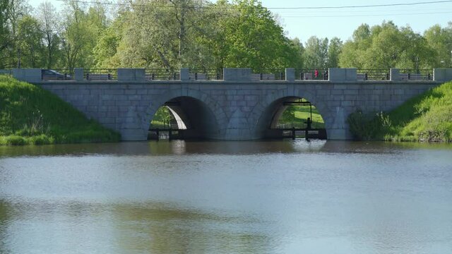 Stone bridge Marienthal pond Slavyanka river in Pavlovsk park on sunny spring day, Saint Petersburg, Russia.