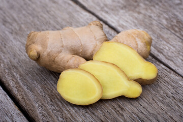 Fresh organic ginger root ( rhizome ) with slice isolated on rustic wood table background.