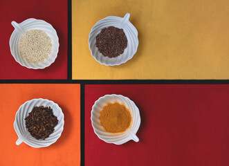 Spices and grains in white cups on colorful napkins. Top view