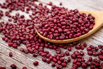 Red beans in a wooden spoon on wood table.