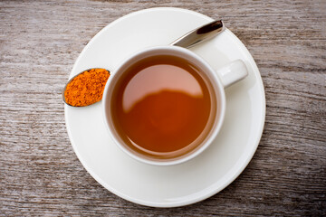 Cup of Tumeric tea isolated on wood table. Top view.