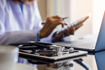 Female doctor working with computer, using calculator for account medicals cost and fees.