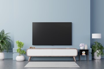 TV on the cabinet in modern living room have plants and book on blue wall background.
