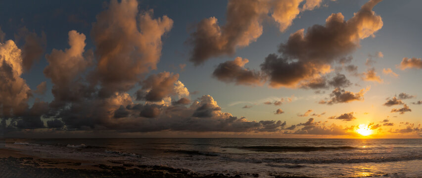 Shocking sun drop with vibrant colors. Golden clouds at sunset. Vacation landscape in the tropics.