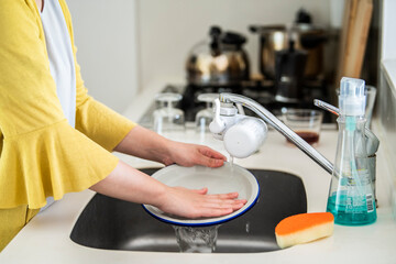 流しで皿を洗う女性の手元