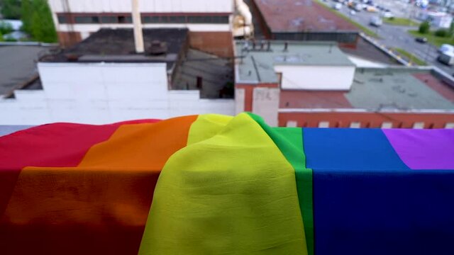 A close-up of the LGBT community symbol gay pride rainbow hangs on a window overlooking the street. Concept of minority rights in the world