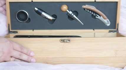 A bartender girl is opening a wine tool kit in a wooden box