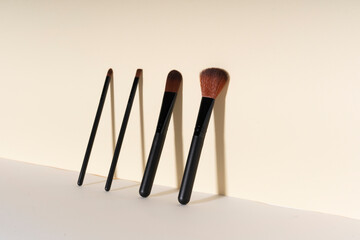Cosmetic brushes leaning on yellow wall. Copy space.