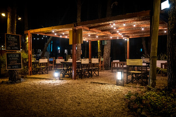 Fototapeta na wymiar Night scene of an elegant outdoor bar illuminated by small hanging bulbs