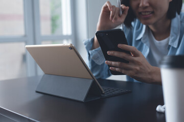 Asian business woman using mobile phone working on digital tablet and laptop computer at home