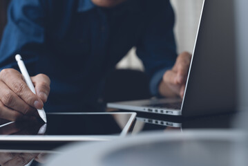 Man graphic designer working on laptop computer and digital tablet in office